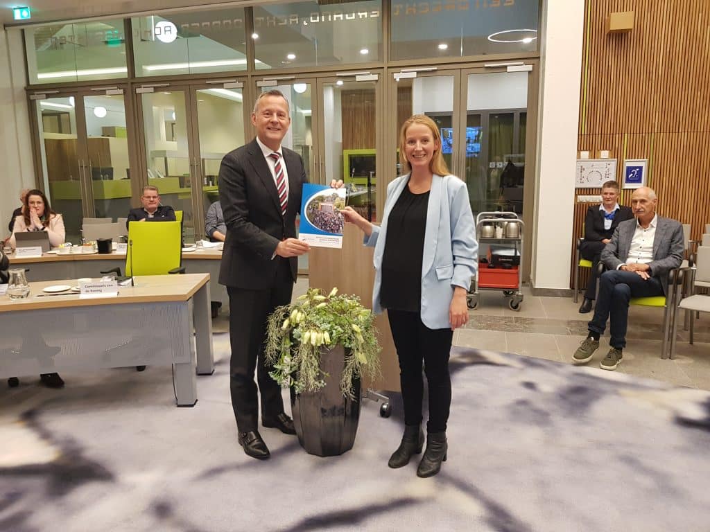 Commissaris Arthur van Dijk ontvangt de profielschets voor de nieuwe burgemeester uit handen van Maartje Tros, fractievoorzitter van de Seniorenpartij Drechterland